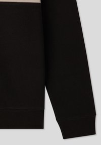 Manica di felpa nera con polsino a costine, caratterizzata da una texture liscia e un design minimale. Nessun motivo visibile o dettagli hardware.