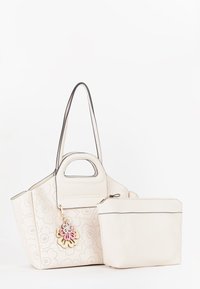 Hvid perforeret læder tote taske med to håndtag, der har en aftagelig blomstercharms og en matchende lynlåspung. Glat overflade.