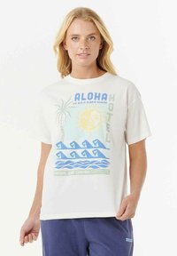 Camiseta de algodón blanca con un estampado colorido de palmeras, sol y olas. El texto dice "ALOHA HOTEL" y "EL SOL SIEMPRE BRILLA."