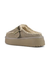 Mocassin en daim marron avec doublure en shearling, semelle en caoutchouc épaisse, couture décorative et accent de boucle en métal sur le dessus.