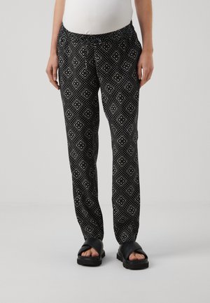 Pantaloni neri con un design geometrico, vita elastica e tasche laterali. Abbinati a sandali neri piatti. Morbida texture del tessuto.