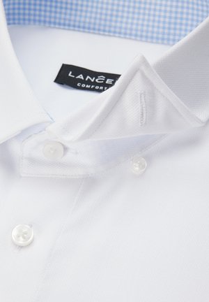 Biała bawełniana koszula z fakturowanym wykończeniem, z niebieskim, kratkowanym wewnętrznym kołnierzykiem i dwoma białymi plastikowymi guzikami na plisie.