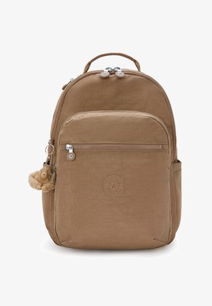 Mochila de nailon marrón con un bolsillo frontal con cremallera, asa de transporte y un llavero de mono peludo. Presenta un logo redondo en el frente.