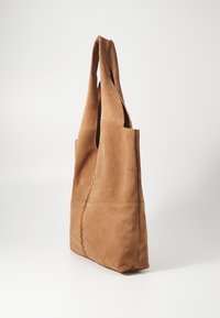 Bruine suède totebag met een zachte textuur, twee schouderbanden en een gestikte afwerking langs de naad. Ontwerp zonder deksel met geen hardware.