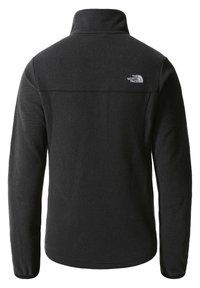 Svart fleecejacka med hög krage, texturerat tyg och en logotyp på övre ryggen. Har långa ärmar och en något rundad nederkant.