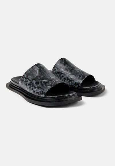 Zwarte sandalen met een krokodillenleerpatroon, open teen, platte zool en minimalistisch ontwerp. Duurzaam materiaal en moderne vorm.