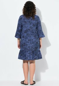 Abito blu a fantasia con orlo svasato e maniche a campana a tre quarti. Il tessuto mostra illustrazioni dettagliate in toni più scuri.