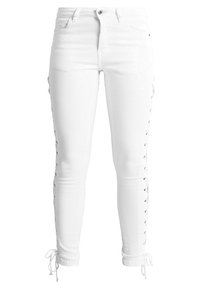 Leggings de mezclilla blanca con un corte ajustado, que cuentan con detalles de cordones a lo largo de los lados y lazos ajustables en los tobillos. Textura suave.