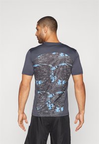 Short-sleeve athletic shirt in dark gray with a patterned back featuring blue accents and a textured fabric design.