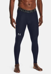 Marineblauwe vochtregulerende leggings met een aansluitend ontwerp. Voorzien van een gemarkeerde grijze tailleband en een klein wit logo op de linker bovenbeen.