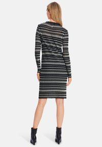 Schwarz-weißer, gestreifter Langarmkleid mit figurbetonter Form, knielangem Saum und gerundetem Ausschnitt. Durchsichtiges Material und vertikale Muster.