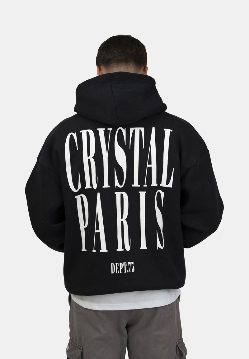 Sudadera negra con texto blanco en la parte posterior: "CRYSTAL PARIS" y "DEPT.75." Presenta una gran capucha y un corte relajado, confeccionada en tela suave.