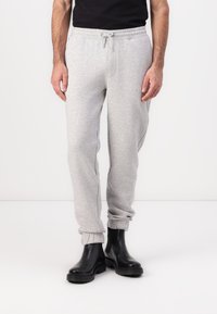 Light gray sweatpants with elastic cuffs, drawstring waist, and a soft textured fabric, paired with black rubber ankle boots.