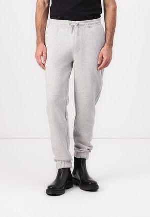 Light gray sweatpants with elastic cuffs, drawstring waist, and a soft textured fabric, paired with black rubber ankle boots.