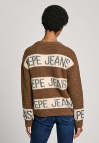 Maglione marrone lavorato a maglia con strisce crema e blu e testo "PEPE JEANS". Vestibilità ampia con colletto tondo e polsini a costine.