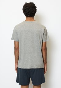 Graues Baumwoll-T-Shirt mit kurzen Ärmeln, Rundhals-Ausschnitt und lockerer Passform, von hinten betrachtet, mit sichtbaren dunklen Shorts.