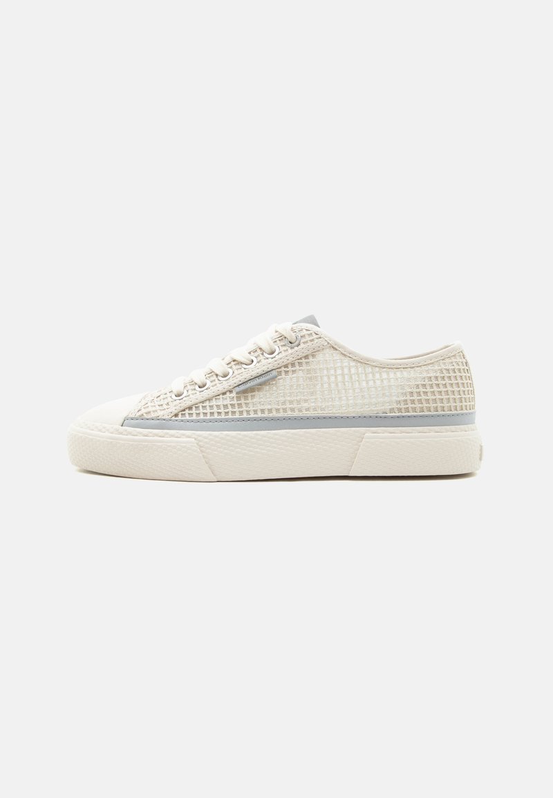 Μπεζ αθλητικό παπούτσι χαμηλού ύψους με λευκή λαστιχένια σόλα, επάνω μέρος από δίχτυ, κλείσιμο με κορδόνια και γκρι ρίγα στο πλάι.