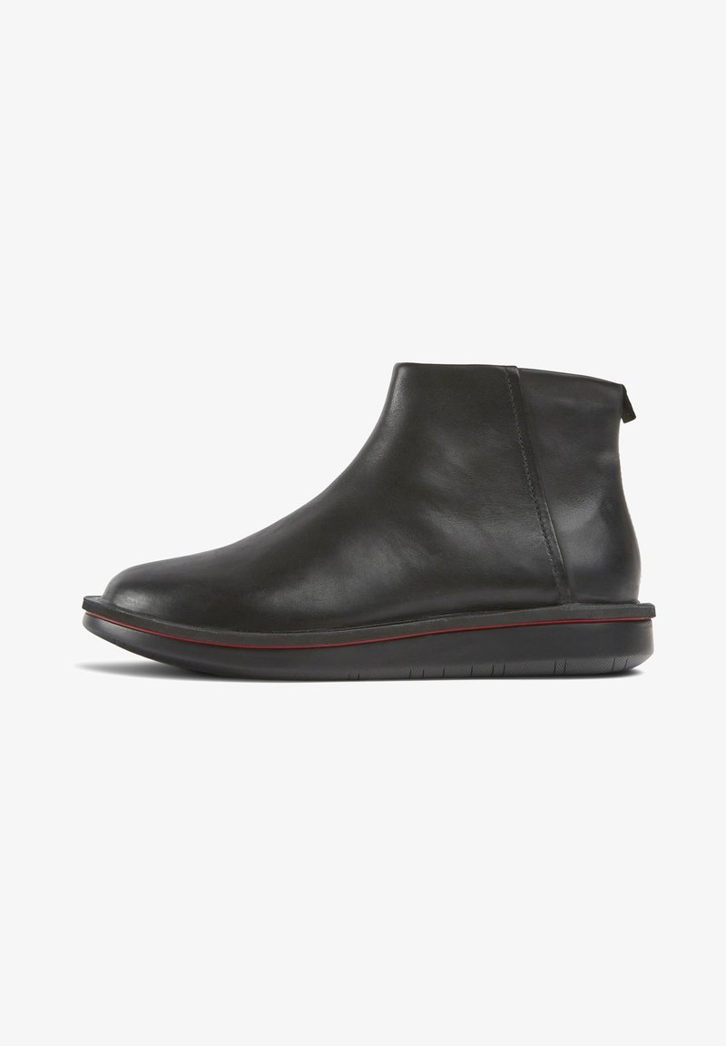 Black leather ankle boot with rounded toe, flat sole with thin red stripe, and pull tab at the back, shown in side profile on white background.