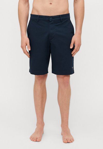 Shorts in cotone blu navy con chiusura a bottone e zip, caratterizzati da due tasche frontali e un logo sull'orlo, design lungo fino al ginocchio.