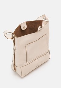 Sac fourre-tout en cuir beige avec un extérieur lisse, doublure en daim marron, fermeture à pression sur le côté et poche extérieure. Accents en métal argenté.