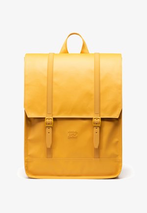 Sac à dos jaune avec une finition brillante, doté de deux bretelles réglables, d'une poignée supérieure et d'un rabat avant avec des boucles. Marquage visible en bas.