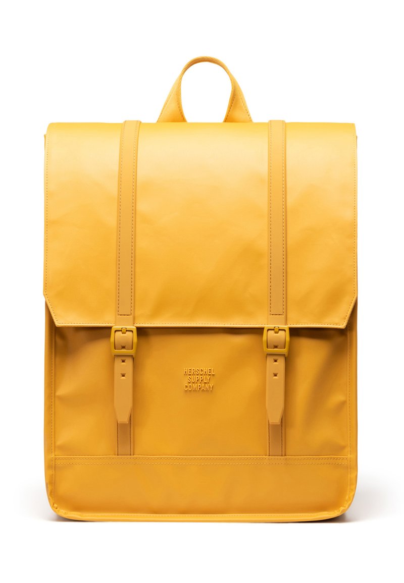 Sac à dos jaune avec une finition brillante, doté de deux bretelles réglables, d'une poignée supérieure et d'un rabat avant avec des boucles. Marquage visible en bas.