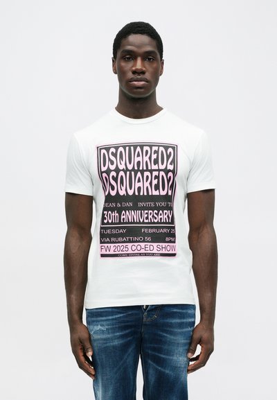 Mann in weißem T-Shirt mit pinkem und schwarzem Grafiktext über die 30. Jubiläumsmodenschau von Dsquared2, kombiniert mit blauen Jeans.