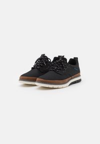 Black athletic shoes with a breathable mesh upper, brown synthetic accents, black laces, and a cushioned white sole, featuring a textured design.