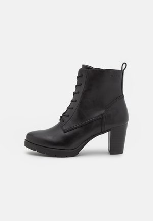 Schwarze Leder-Boots bis zum Knöchel mit runder Zehenform, Schnürung vorne, kräftigem Absatz und kontrastierender Sohle; verfügt über eine Nähte-Detaillierung und eine Zuglasche.