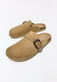 Světlohnědé semišové nazouvací dřeváky s nastavitelnými pásky na černé kovové přezky a texturovanými béžovými pryžovými podrážkami.