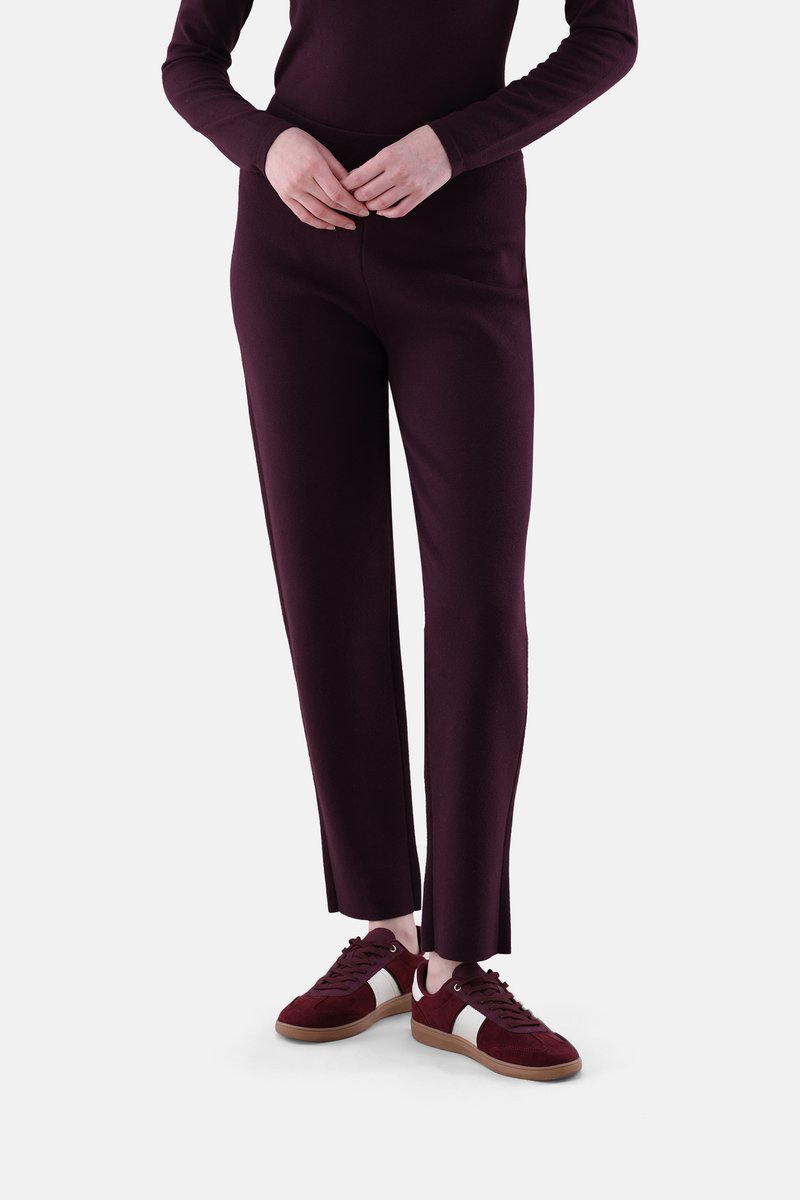 Bordeauxroter Pullover und passende Hose aus Strickstoff, mit hoher Taille und geradem Bein. Kombiniert mit bordeauxroten und weißen Turnschuhen.
