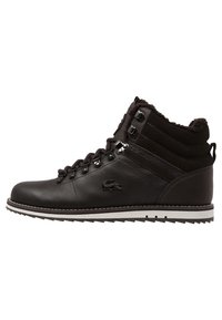 Bota de senderismo de cuero marrón oscuro con forro de piel, ojales de metal, suela texturizada y logo de cocodrilo bordado en el lateral.