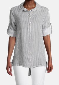 Camicia a righe bianca e nera con colletto, maniche arrotolate e orlo leggermente curvo. Tessuto morbido e leggero.
