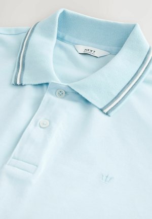 Polo bleu clair en tissu texturé. Doté d'un col classique avec des rayures grises et blanches, de deux boutons et d'un petit logo en forme de couronne.