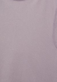 Gros plan d'un top sans manches violet clair montrant une texture de tissu douce et des coutures visibles le long des emmanchures et du col.