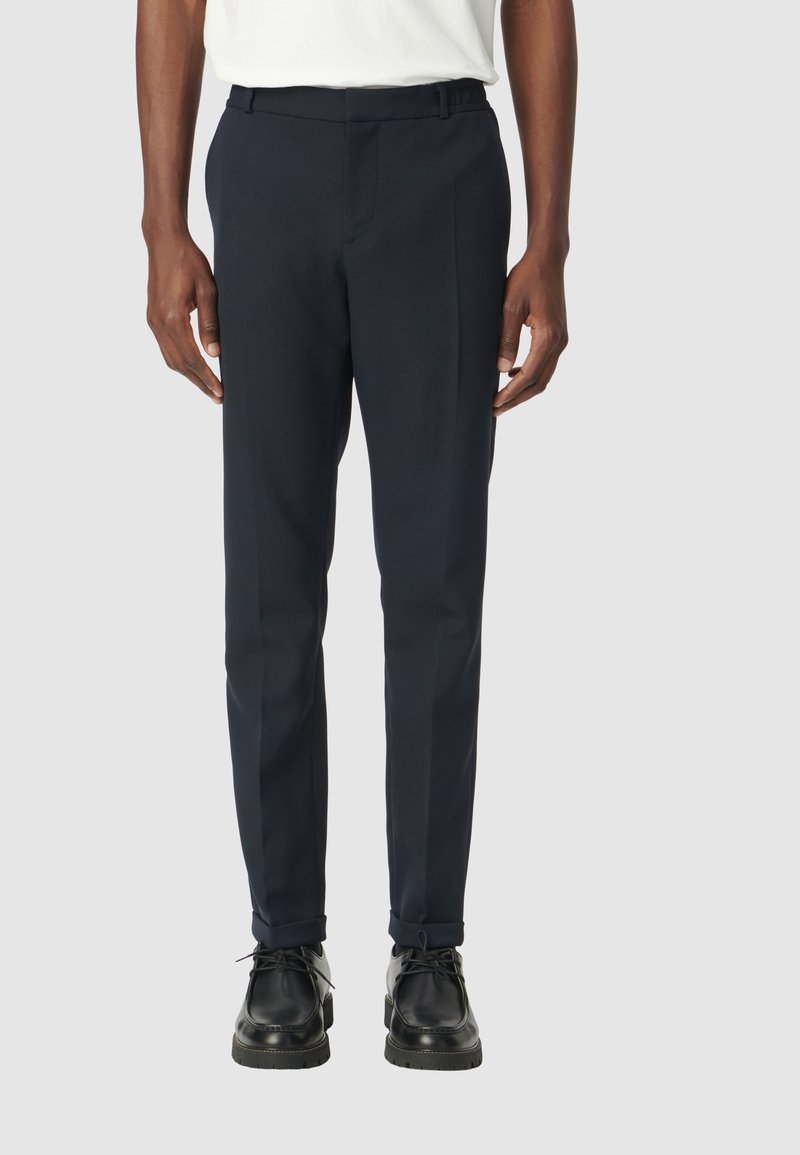 Marineblauwe op maat gemaakte broek van soepel materiaal, met een rechte pasvorm, broeklussen en een persnaad, gecombineerd met zwarte schoenen.
