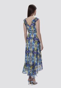 Blumenkleid im Maxiformat mit V-Ausschnitt, schwingenden Ärmeln und fließender Silhouette in Blau-, Gelb- und lila Tönen; leichtes, durchsichtiges Material.