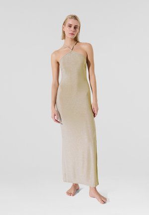 Halter neck, floor-length dress in shimmering light gold fabric with a slim fit, featuring a slit on the left side and smooth texture.