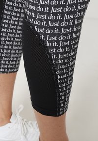 Czarne legginsy z powtarzającym się białym wzorem tekstowym "Po prostu zrób to", z teksturowanym siateczkowym panelem na zewnętrznej stronie nogi dla lepszej wentylacji.