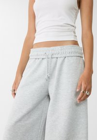 Lichtgrijze sweatpants met een elastische tailleband, trekkoorddetails en een wijd-pijpen ontwerp. Gemaakt van een zachte katoenmix.