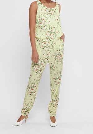 Kwiatowy kombinezon wykonany z jasnoróżowej tkaniny z delikatnym wzorem różowych i białych kwiatów, elastycznym paskiem w talii oraz mankietami na kostkach.