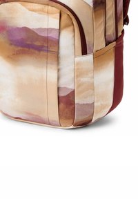Reppu pehmeästä kankaasta, jossa on abstrakti akvarellimuotoilu beige-, ruskea- ja violettisävyissä; siinä on sivutasku ja viininpunaisia yksityiskohtia.