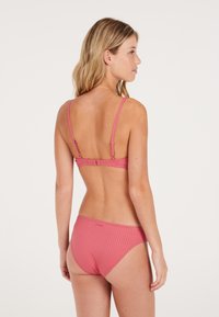 Set di bikini rosa a coste con spalline sottili regolabili e un pantaloni a vita bassa, entrambi con una sottile trama e un design minimalista.