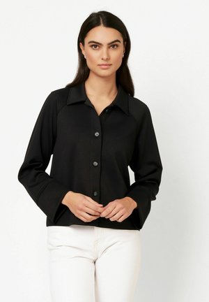 Black button-up shirt with a collared neckline, long sleeves, and flared cuffs, made from smooth fabric. Designed for a relaxed fit.