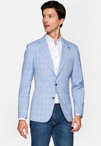 Jasnoniebieska, w kratkę marynarka uszyta z materiału o gładkiej fakturze, z dwiema guzikami i klapami, w połączeniu z białą koszulą.