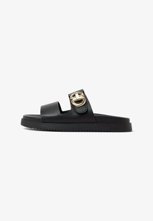 Sandale glissante en cuir noir avec une large sangle et un détail de boucle dorée, dotée d'une semelle noire épaisse et d'un motif texturé.