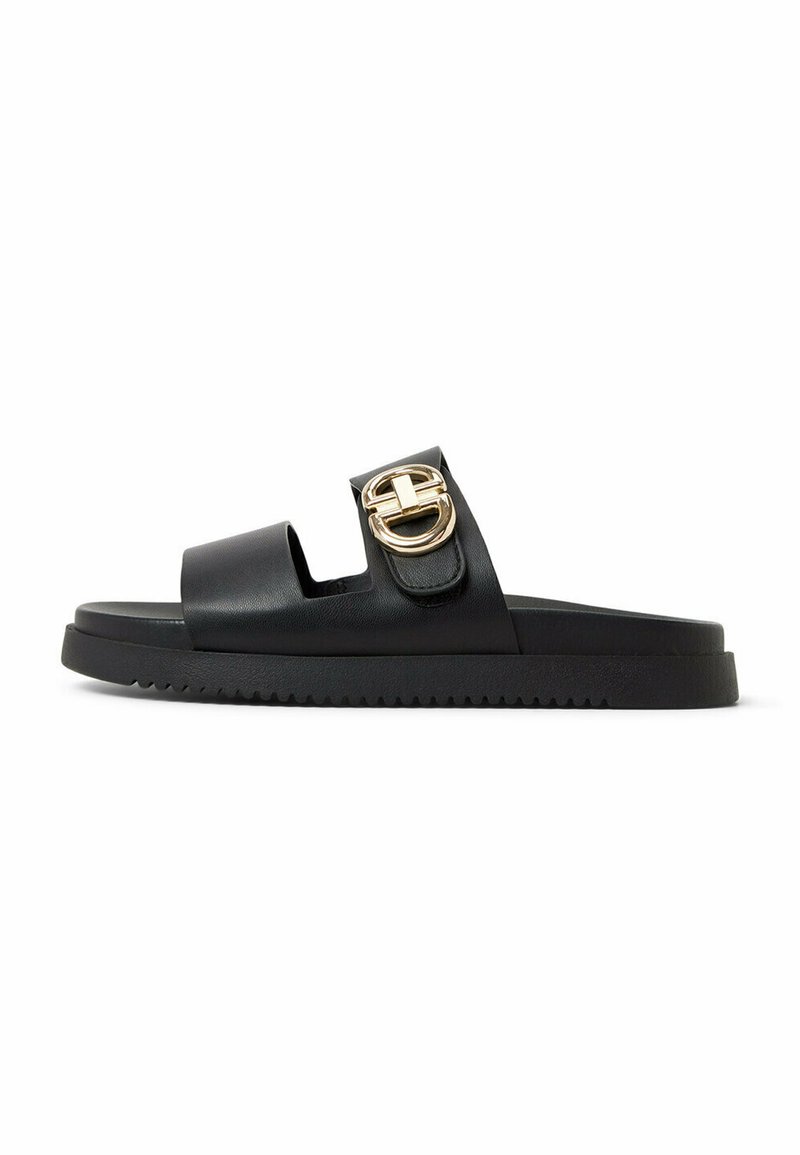 Sandale glissante en cuir noir avec une large sangle et un détail de boucle dorée, dotée d'une semelle noire épaisse et d'un motif texturé.