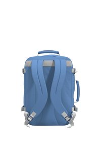 Zaino blu con spallacci imbottiti, maniglia superiore, accenti grigi e superficie in tessuto testurizzato. Presenta fibbie laterali regolabili.