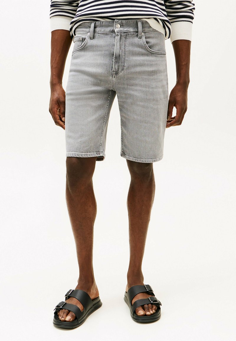 Grijze denimshorts met een klassieke snit, vijf zakken en een licht vervaagde afwerking, in combinatie met zwarte platte sandalen met gespsaccenten.