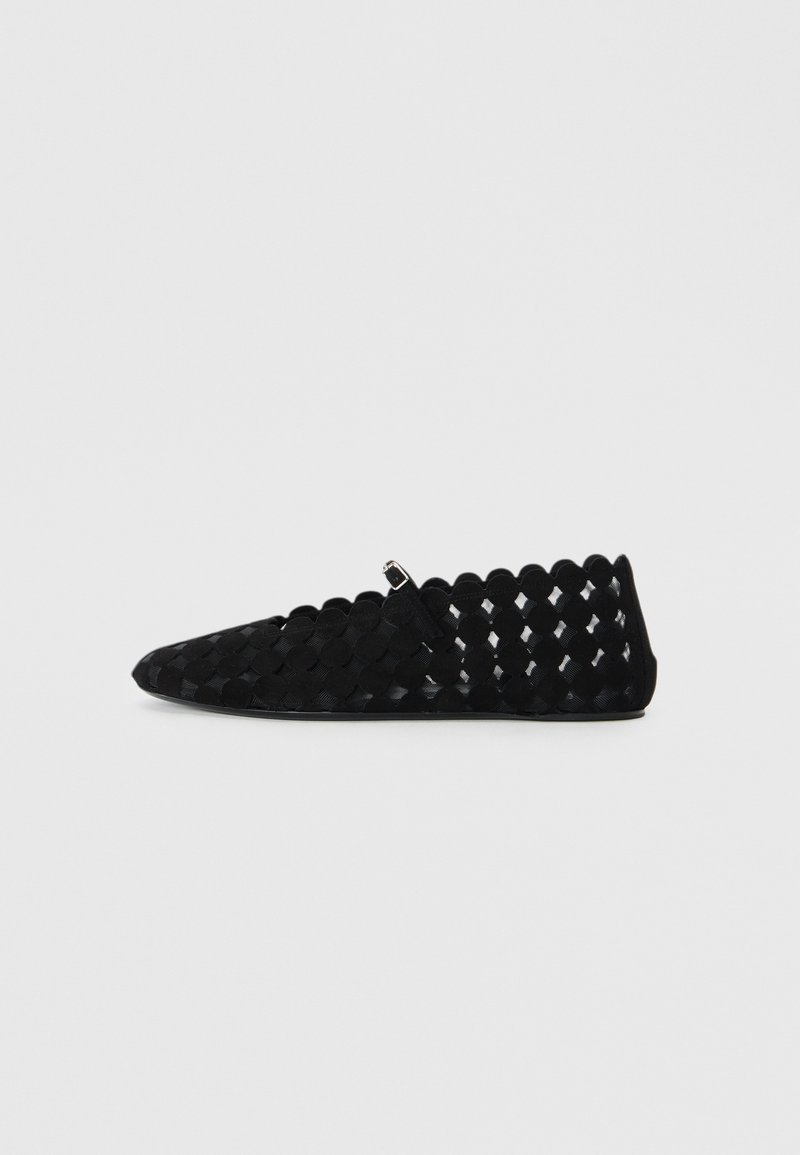 Black woven flats with a pointed toe, scalloped edges, and a small decorative buckle. Made of soft fabric, featuring an open design.